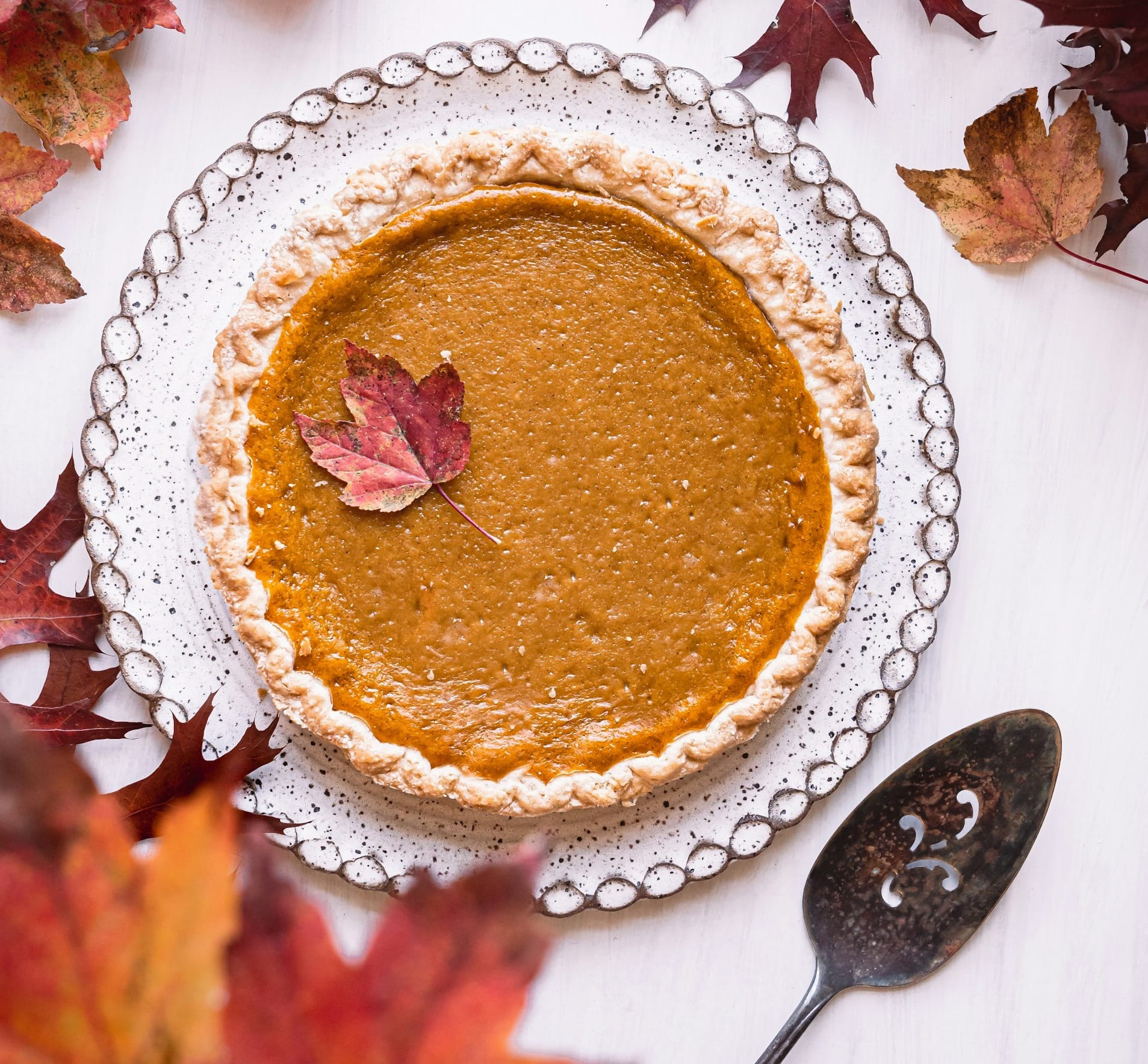 a pie sitting on top of a white table next to leaves