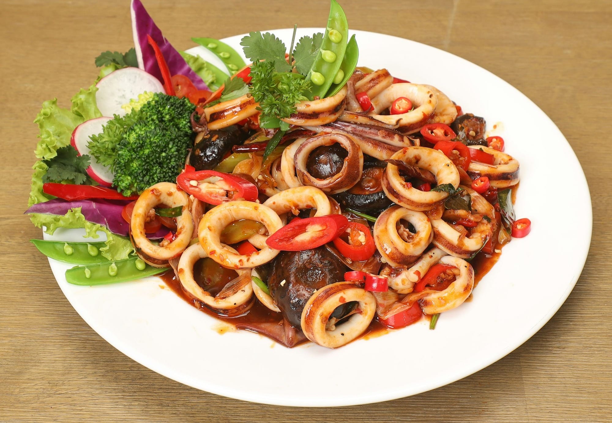 a white plate topped with lots of food on top of a wooden table